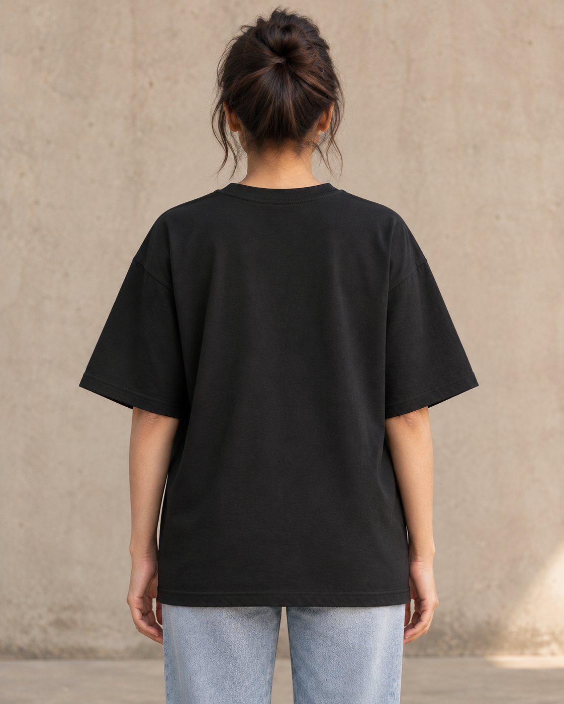 Styling illustration · plain back view · Black Qikink UC22 oversized T-shirt on an Indian adult model. Shared view of the same unprinted garment surface; not a produced-sample photograph.