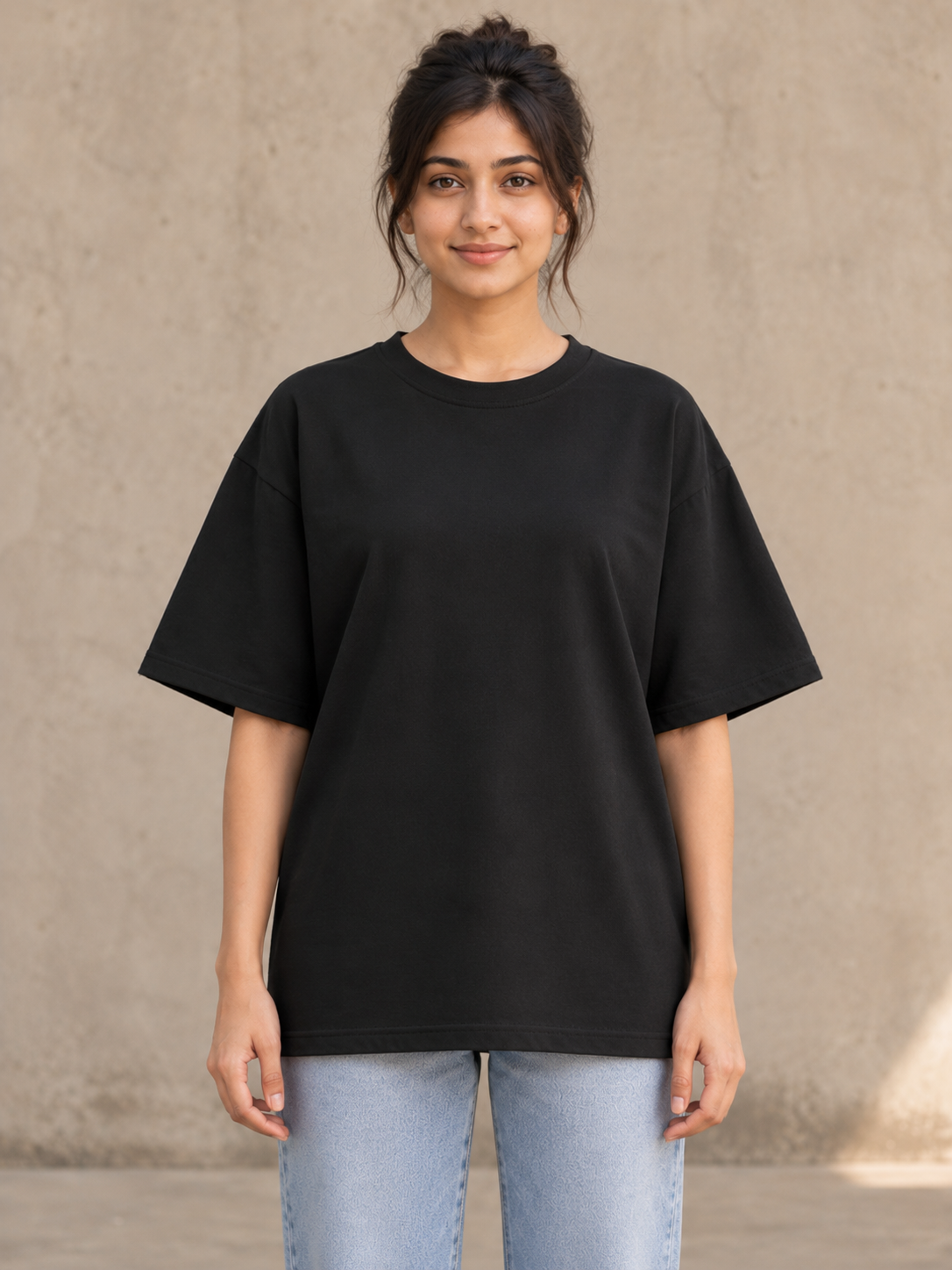 Styling illustration · plain front view · Black Qikink UC22 oversized T-shirt on an Indian adult model. Shared view of the same unprinted garment surface; not a produced-sample photograph.