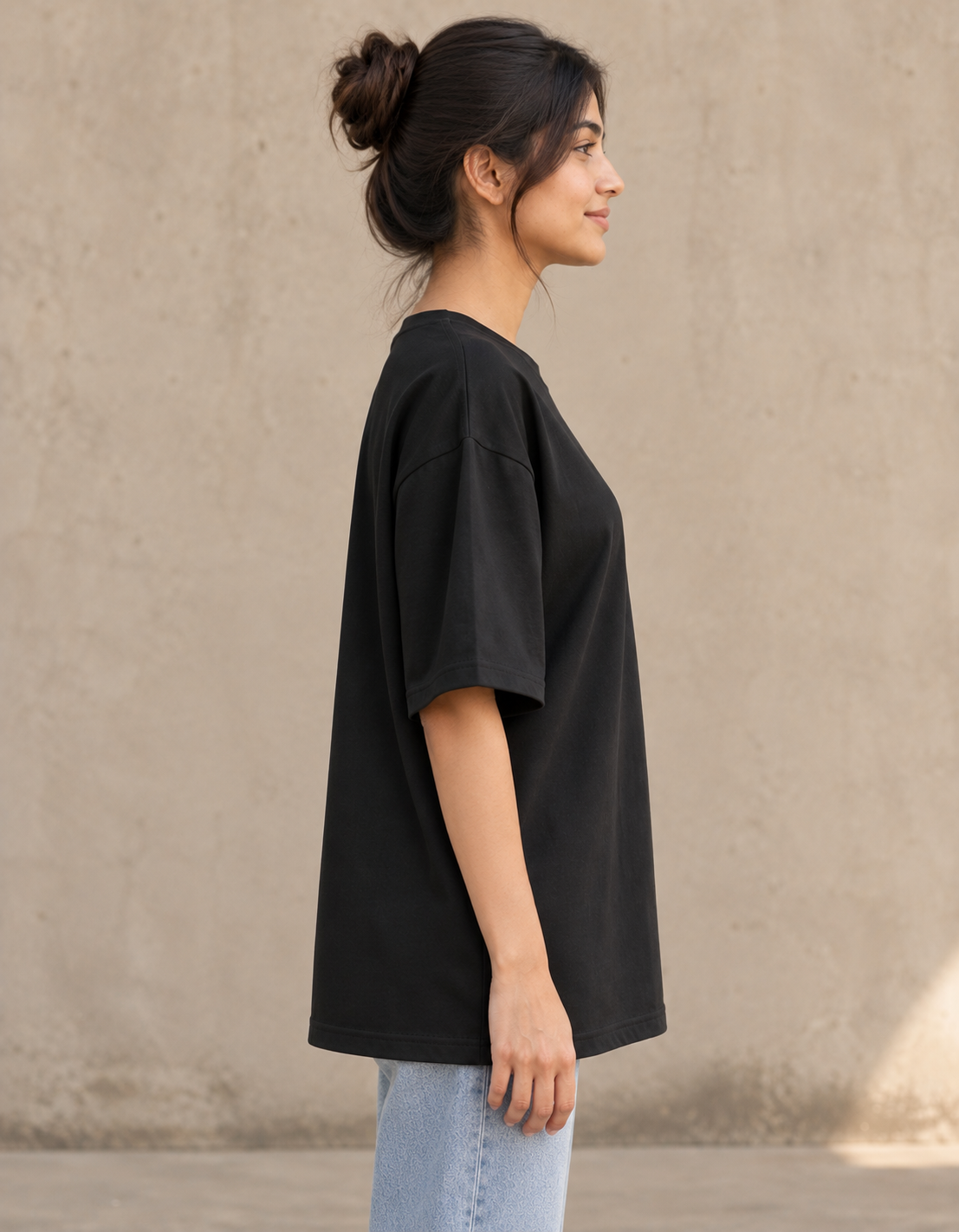 Styling illustration · right side profile · Black Qikink UC22 oversized T-shirt on an Indian adult model. Shared view of the same unprinted garment surface; not a produced-sample photograph.