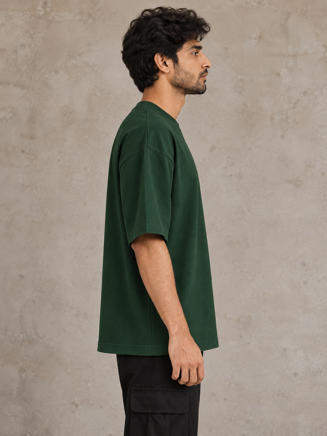Styling illustration · right side profile · Bottle Green Qikink UC22 oversized T-shirt on an Indian adult model. Shared view of the same unprinted garment surface; not a produced-sample photograph.
