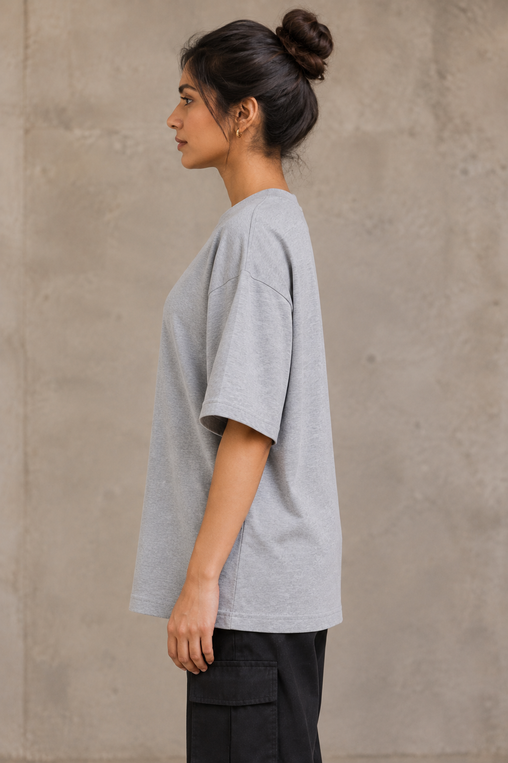 Styling illustration · left side profile · Grey Melange Qikink UC22 oversized T-shirt on an Indian adult model. Shared view of the same unprinted garment surface; not a produced-sample photograph.